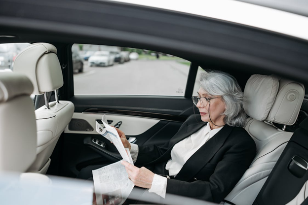 A businesswoman reads a newspaper in a car
