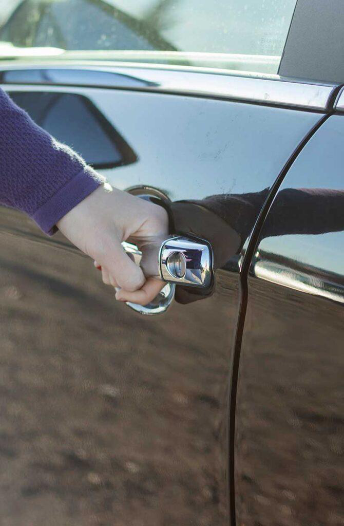 A person opening a car door with the handle 