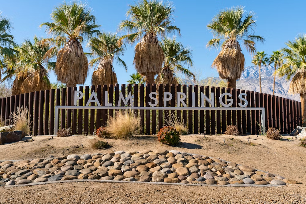 A sign for Palm Springs on a fence 