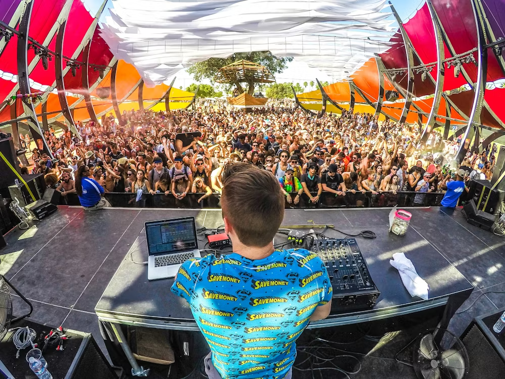 A DJ on a stage in front of a large crowd 