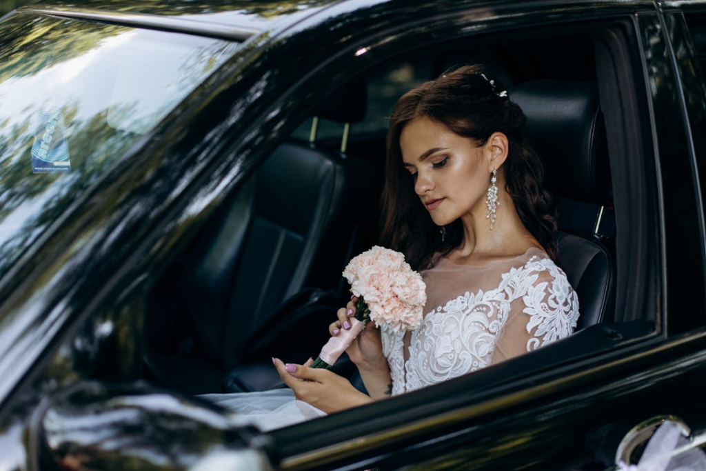 Bride sitting inside luxury car holding bouquet