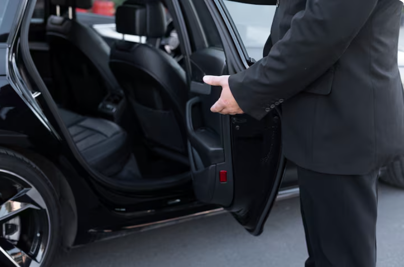 Professional chauffeur standing beside an opened car door ready to assist a passenger