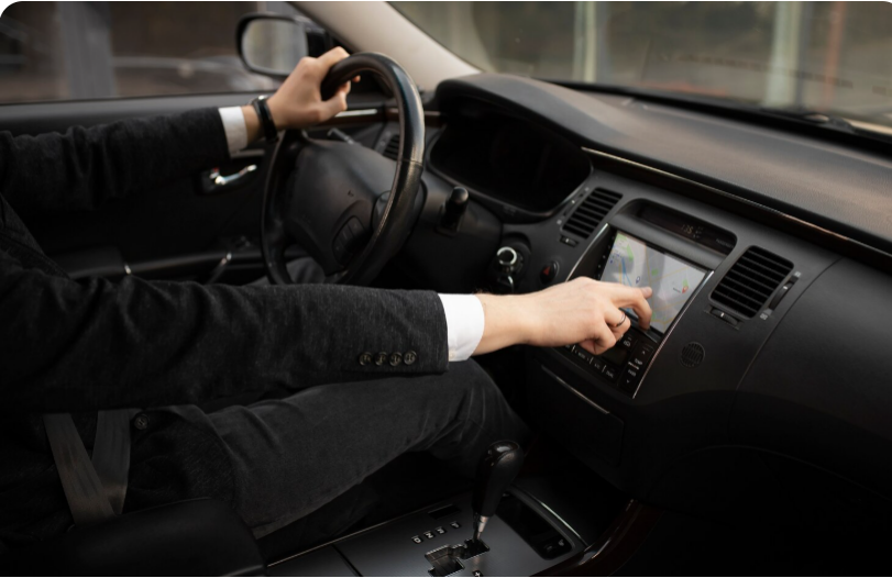 Professional chauffeur adjusting in-car controls and navigation options while driving a luxury vehicle